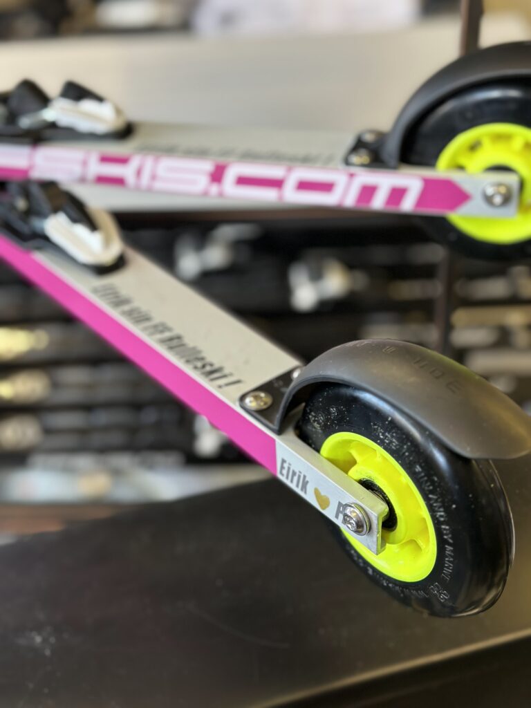 Rollerskier in motion, pushing off with poles on a paved road.