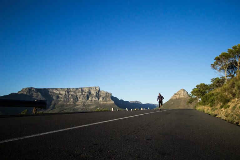Person running on a road with mountains in the background.
